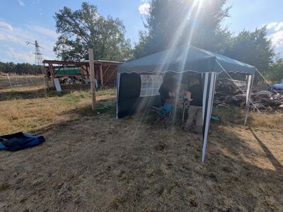 Zwei Personen unter einem Pavillon, Sonnenstrahlen brechen ins Bild.