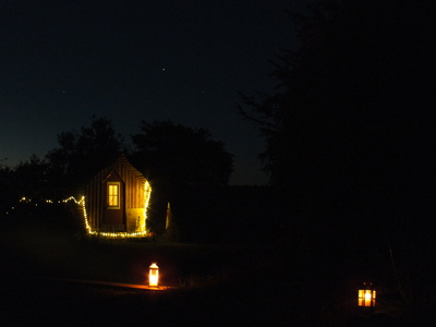 Hütte, Umrandung beleuchtet in der Nacht. Es gab natürlich auch feste Unterkünfte wie diese Faß-Hütte.