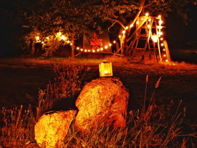 Durch Lichterketten hell beleuchteter Weg. Auch eine Kerze auf einem Stein leuchtet den Weg.