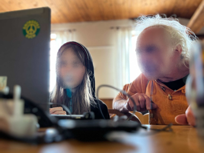 Zwei Personen sitzen konzentriert vor einem Laptop und hacken.