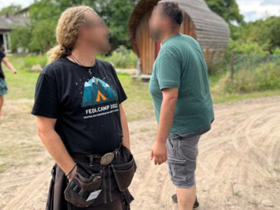 Zwei Personen begegnen sich auf dem Camp. Die Sonne scheint.