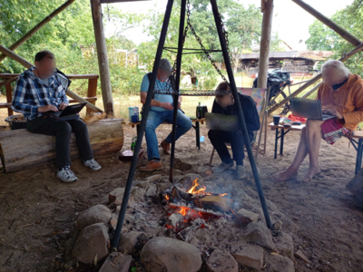 Menschen sitzen um das Lagerfeuer mit jeweils einem Laptop.