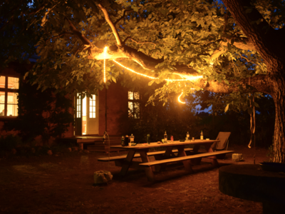 Mit Lichterketten beläuchteter Baum und Tisch.