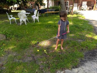Ein Kind hält einen Crossgolf-Schläger in der Hand und spielt.
