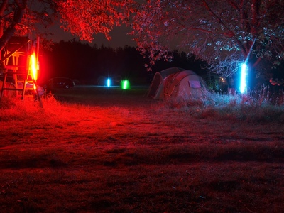 Eingang zum Zeltplatz, hell rot und blau beleuchtet bei Nacht.